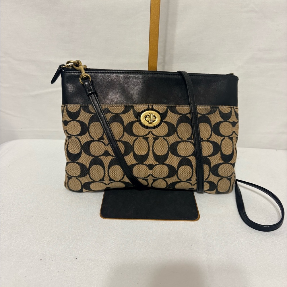 Canvas crossbody bag in khaki and black with a turnlock closure.